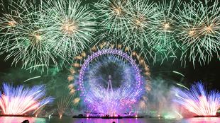Зеленые и фиолетовые новогодние фейерверки окружают Лондонский глаз. 