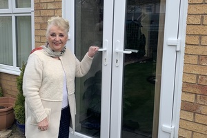 Рита Тейлор, 79 лет, собирается открыть дверь своего патио и войти в свой дом.