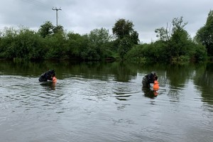 Два человека в реке смотрят вниз на русло реки
